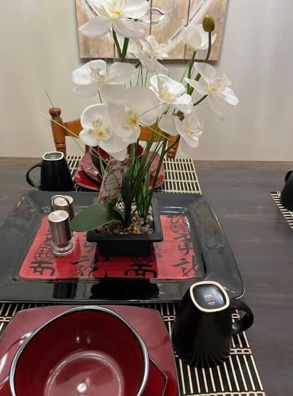 Guests can enjoy a meal for two at this dining area, featuring a table set with a red placemat and a black coffee service.