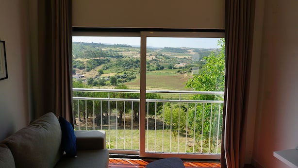 A room with a large sliding glass door leading to a balcony with a view of a green landscape.