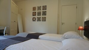 A hotel room with a bed, a desk, and a lamp.
