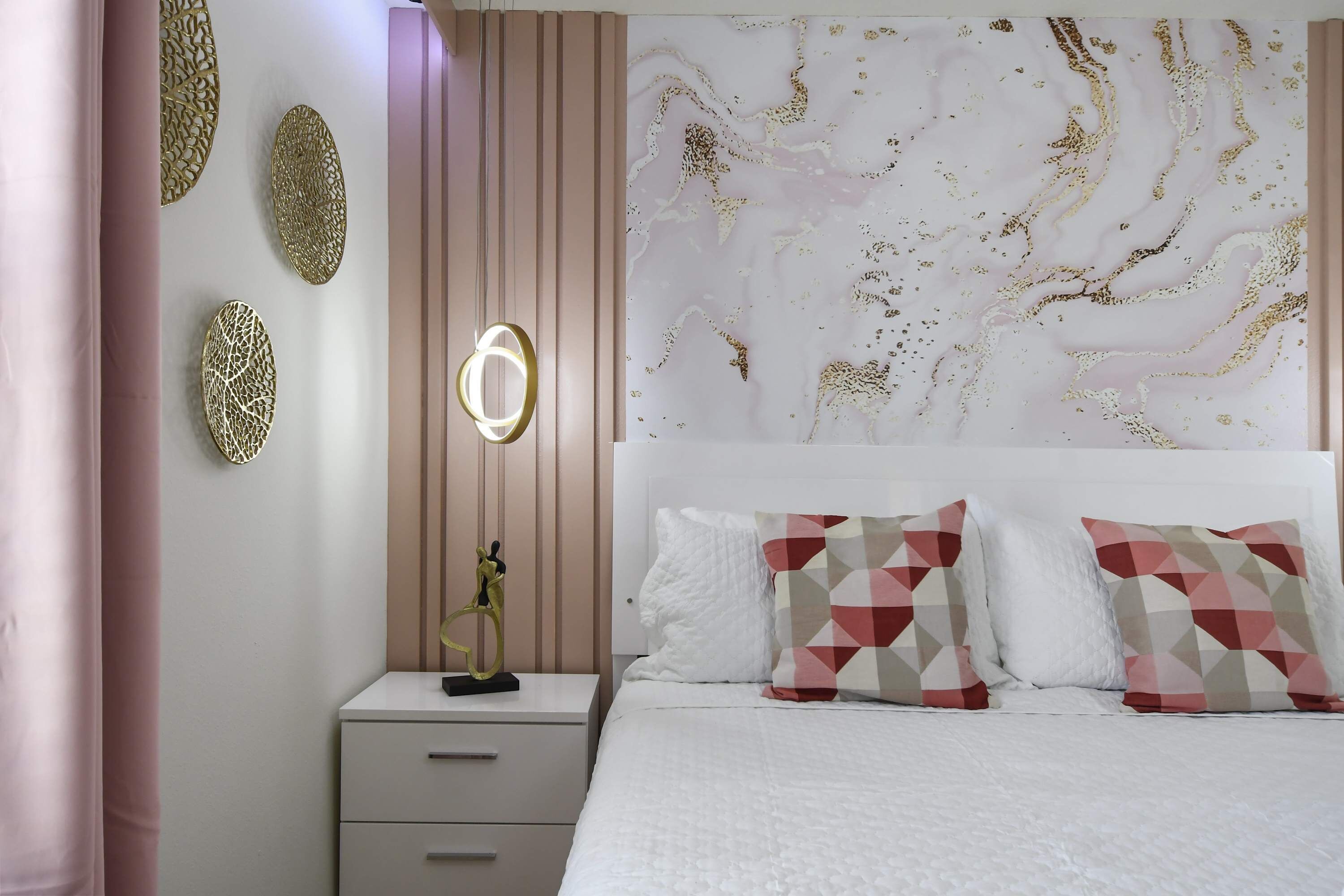 A bedroom with a bed, a nightstand, and decorative wall art.
