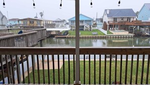 Une terrasse en bois offrant une vue sur un plan d’eau et sur des maisons en arrière-plan.