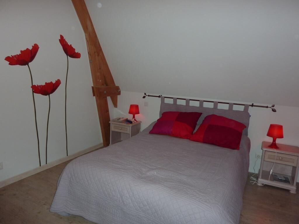 A bedroom with a bed, two bedside tables, and a wall with a floral design.