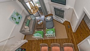 Een moderne woonkamer met een bank, stoelen, een open haard en een eethoek.