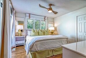 A bedroom with a bed, nightstands, lamps, a ceiling fan, and a window. - Updated condo with balcony view of the golf course! Community Pool (Bald Head Island)