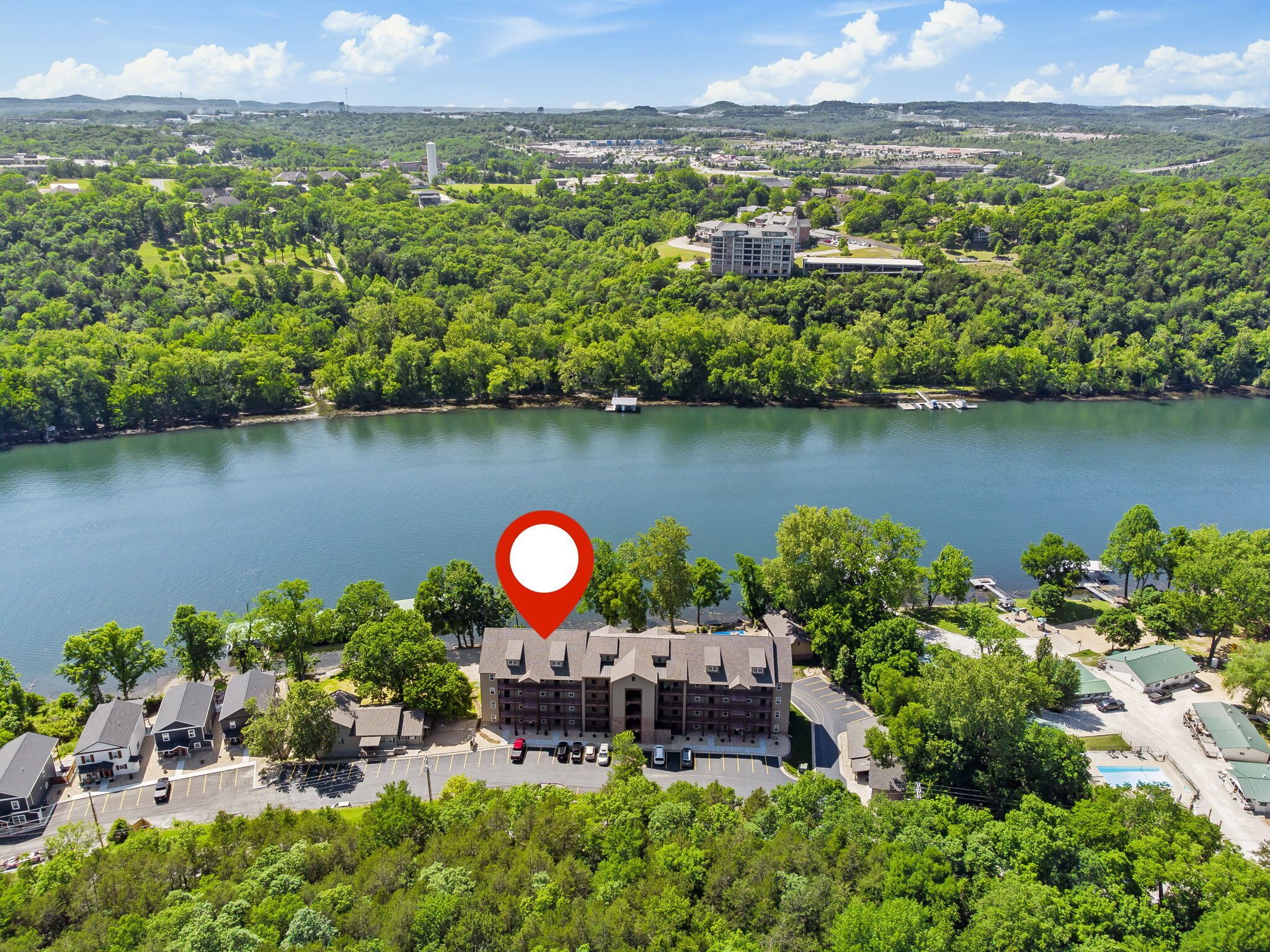 An aerial view of a hotel with a large building surrounded by lush greenery and a lake.