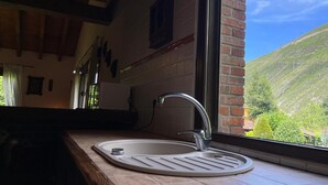 Eine Küche mit Spüle, einem Fenster und Blick auf einen grünen Hügel.