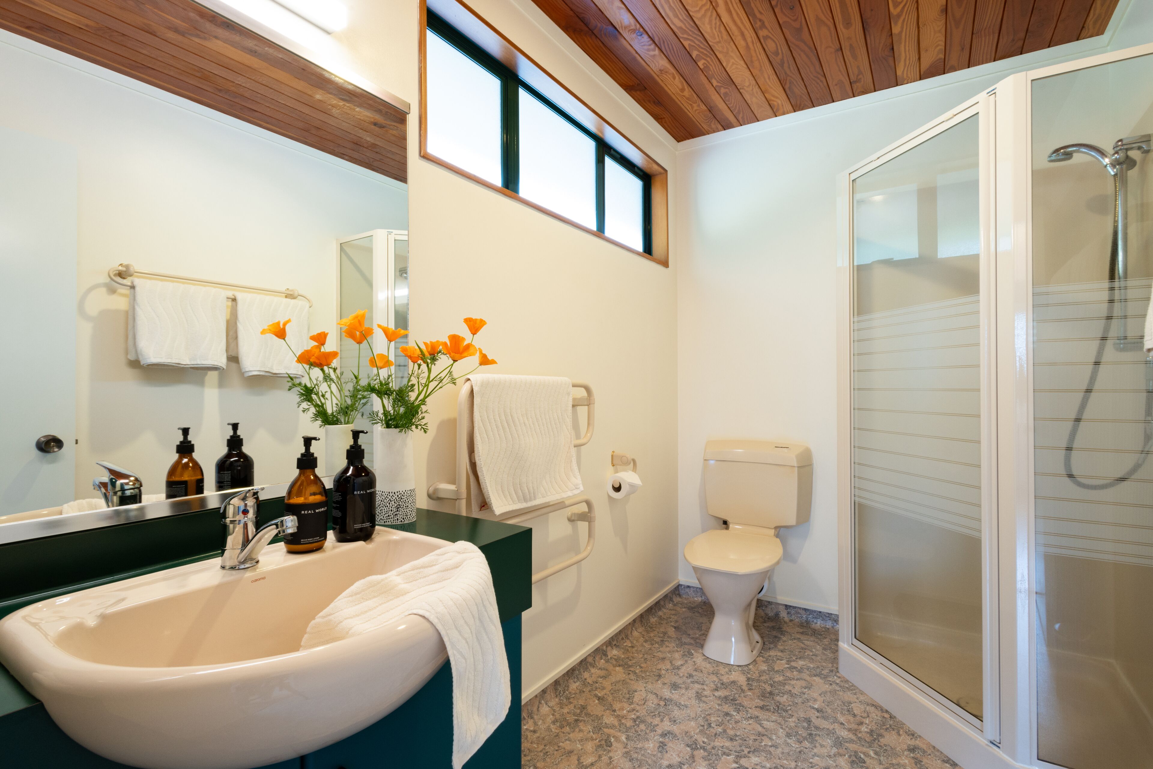 A bathroom with a sink, mirror, toilet, and shower.