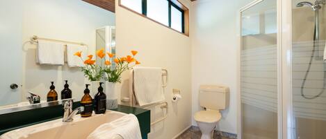 A bathroom with a sink, mirror, toilet, and shower.