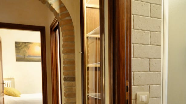 Un couloir avec une porte en bois, un mur en briques et un lit avec un oreiller jaune.