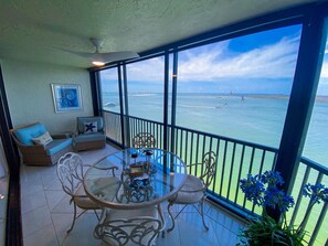 Ein Balkon mit Glastisch und Stühlen, einer Couch und Blick auf das Meer.