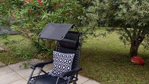 A patio area with a black and white patterned lounge chair, a small table, and a red decorative object on the ground. - A peaceful haven with swimming pool, 20 minutes from Bordeaux and its vineyards. (TRESSES)