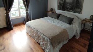 A bedroom with a bed, a window with curtains, a wall-mounted Buddha statue, and a ceiling fan. - A peaceful haven with swimming pool, 20 minutes from Bordeaux and its vineyards. (TRESSES)