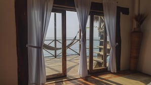 Une chambre avec vue sur la mer, un hamac et une terrasse en bois.
