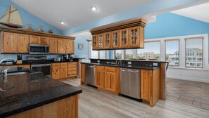 A modern kitchen with wooden cabinets, stainless steel appliances, and a large island. - Atabey-Amazing Home! Private pool, 2 hot tubs, elevator, rec room, ocean views! (Corolla)
