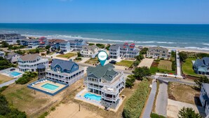 A coastal residential area with multiple houses, a swimming pool, and a view of the ocean. - Atabey-Amazing Home! Private pool, 2 hot tubs, elevator, rec room, ocean views! (Corolla)