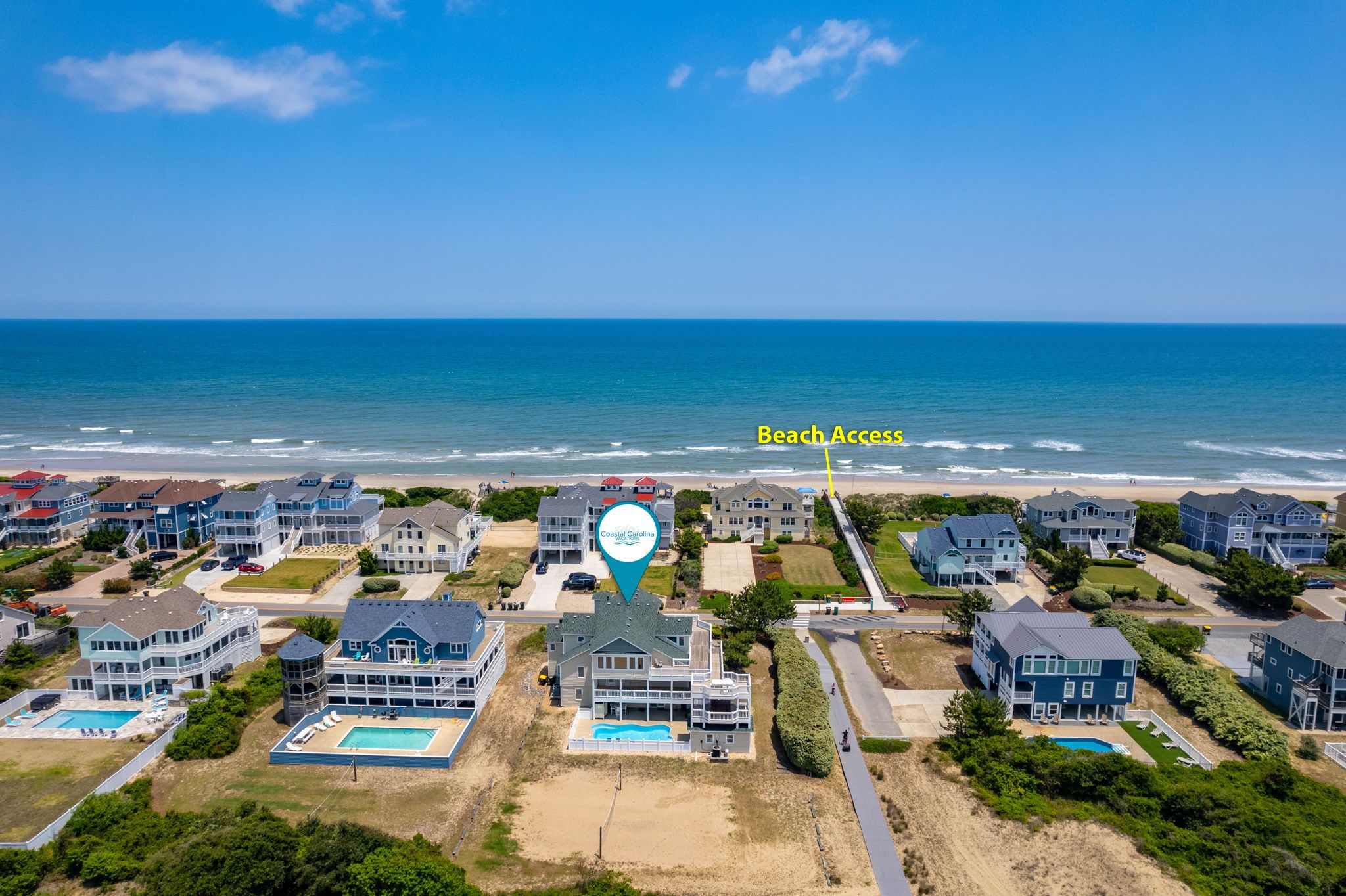 A coastal residential area with beachfront houses, a swimming pool, and a clear view of the ocean.
