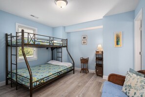 Une chambre avec un lit superposé, une fenêtre, une lampe et une petite table.