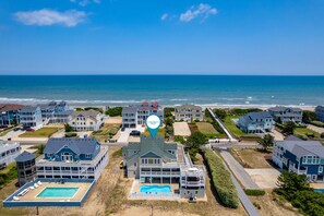 Uma área residencial à beira-mar, com várias casas, piscina e vista para o oceano.