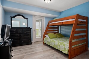 A bedroom with a bunk bed, a dresser, a television, and a door leading to a balcony. - Atabey-Amazing Home! Private pool, 2 hot tubs, elevator, rec room, ocean views! (Corolla)