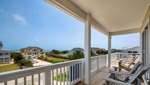 A wooden deck with white railings, overlooking a residential area with houses and a clear sky. - Atabey-Amazing Home! Private pool, 2 hot tubs, elevator, rec room, ocean views! (Corolla)