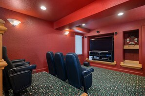 Una sala de cine en casa con paredes rojas, un televisor de pantalla plana grande y varias zonas de estar.