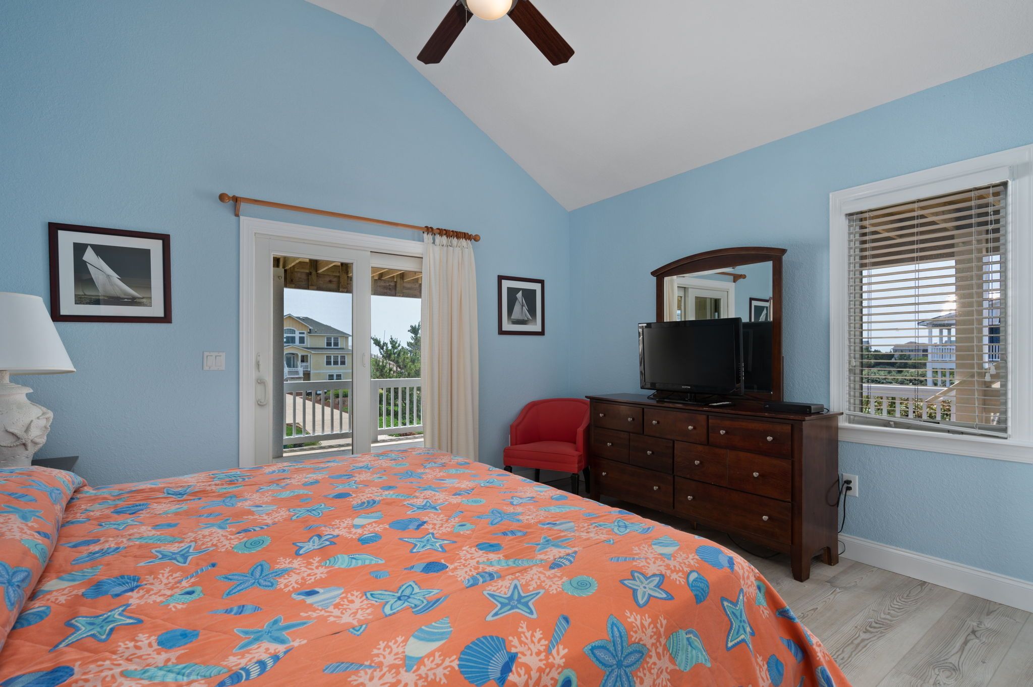 A bedroom with a bed, a dresser, a television, and a window with blinds.