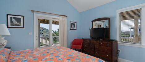 A bedroom with a bed, a dresser, a television, and a window with blinds.