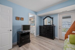 Un dormitorio con televisión, cómoda y espejo.