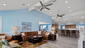 A spacious living room with a large sofa, a coffee table, and a dining area with bar stools. - Atabey-Amazing Home! Private pool, 2 hot tubs, elevator, rec room, ocean views! (Corolla)