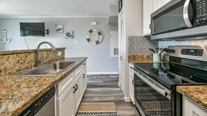 Eine moderne Küche mit Granit Arbeitsplatten, Edelstahlgeräten und einem gemusterten Teppich.