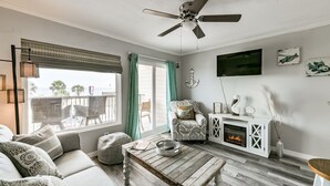 Ein Wohnzimmer mit einer Couch, einem Couchtisch, einem Kamin und einem Deckenventilator.