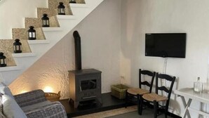 Un salon moderne avec un escalier blanc, une cheminée, un téléviseur à écran plat et des sièges confortables.