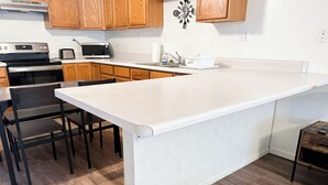 A modern kitchen with wooden cabinets, a white countertop, a built-in microwave, a toaster, and a sink. - Cozy 2BR, 1BA Getaway in Macomb, IL (Macomb)