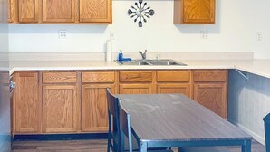 A kitchen with wooden cabinets, a white countertop, a ceiling fan, and a dining table with chairs. - Cozy 2BR, 1BA Getaway in Macomb, IL (Macomb)