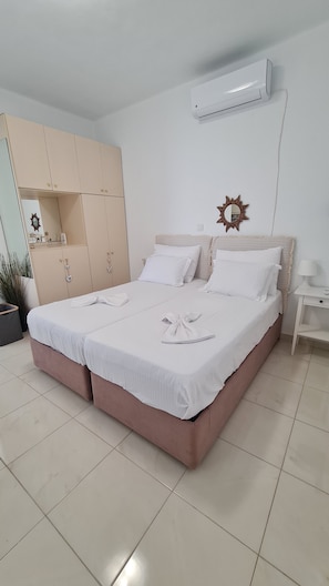 A neatly arranged hotel room with a bed, a wardrobe, a bedside table, and an air conditioning unit. - CASA DI ELSA - STUDIO IN LAMBI, KOS (Kos)