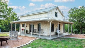 A two-story stone house with a covered porch and a small backyard.