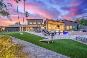 Una casa moderna con piscina, mobiliario exterior y un césped bien cuidado.
