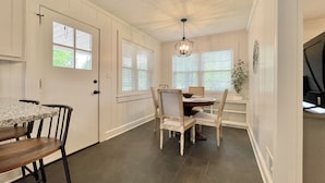 A dining area with a table and chairs, a chandelier, and a window with blinds. - Discover Tranquility at Carolina Cottage - Cozy 2-Bedroom Retreat in Hickory, NC (Hickory)