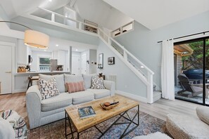 A spacious living area with a light blue sofa, a coffee table, and a staircase leading to an outdoor patio. - Cozy Sapphire Retreat | Fireplace • Dog Friendly (Sapphire)