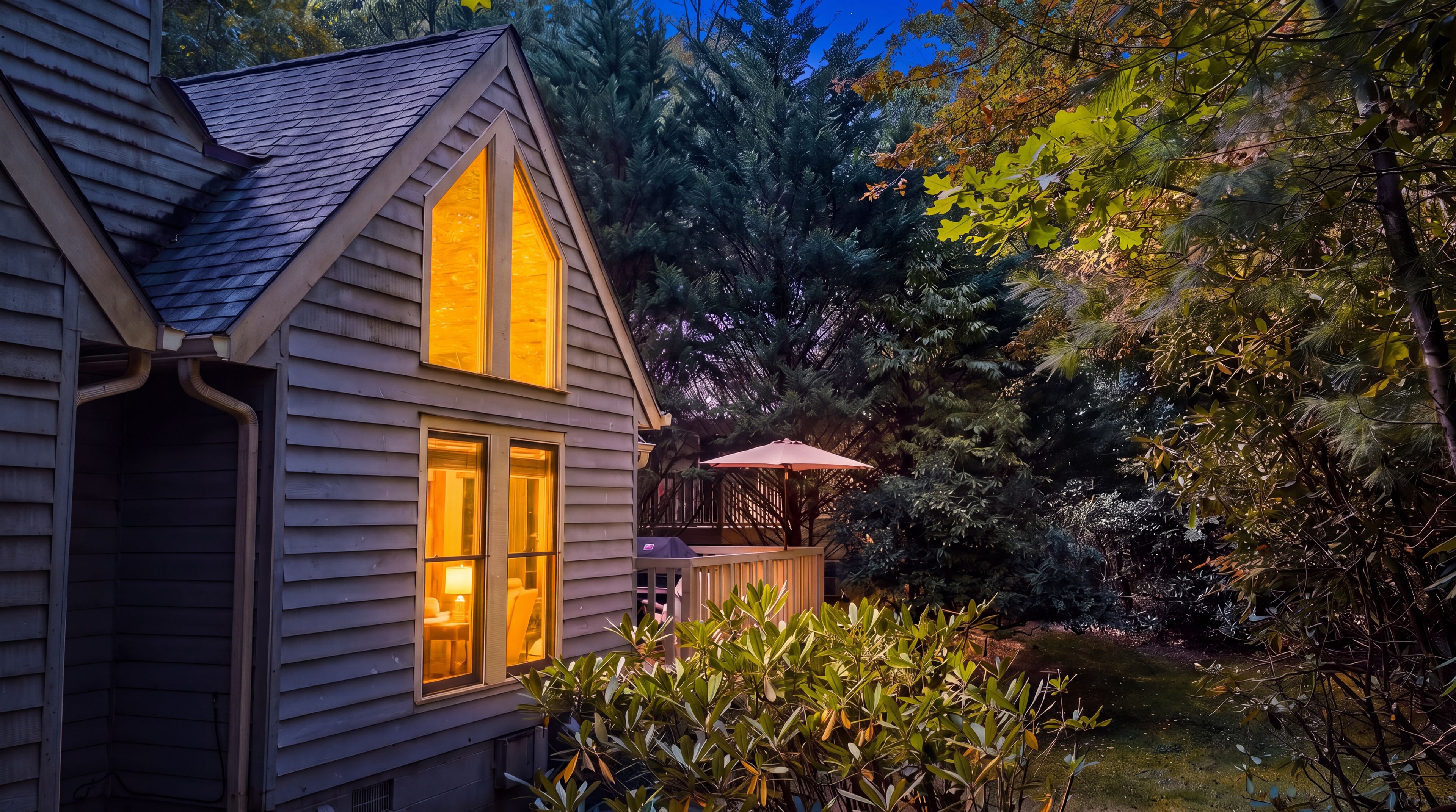 Uma casa com telhado inclinado e uma grande janela com vista para o jardim.