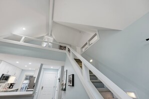A multi-level interior with a staircase, white walls, and a kitchen area. - Cozy Sapphire Retreat | Fireplace • Dog Friendly (Sapphire)