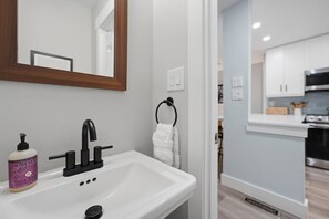 A bathroom with a white sink, black faucet, and a bottle of hand soap. - Cozy Sapphire Retreat | Fireplace • Dog Friendly (Sapphire)