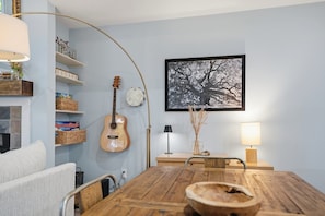 A dining area with a wooden table, chairs, a guitar, and a framed picture on the wall. - Cozy Sapphire Retreat | Fireplace • Dog Friendly (Sapphire)