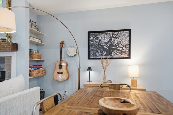 A dining area with a wooden table, chairs, a guitar, and a framed picture on the wall. - Cozy Sapphire Retreat | Fireplace • Dog Friendly (Sapphire)