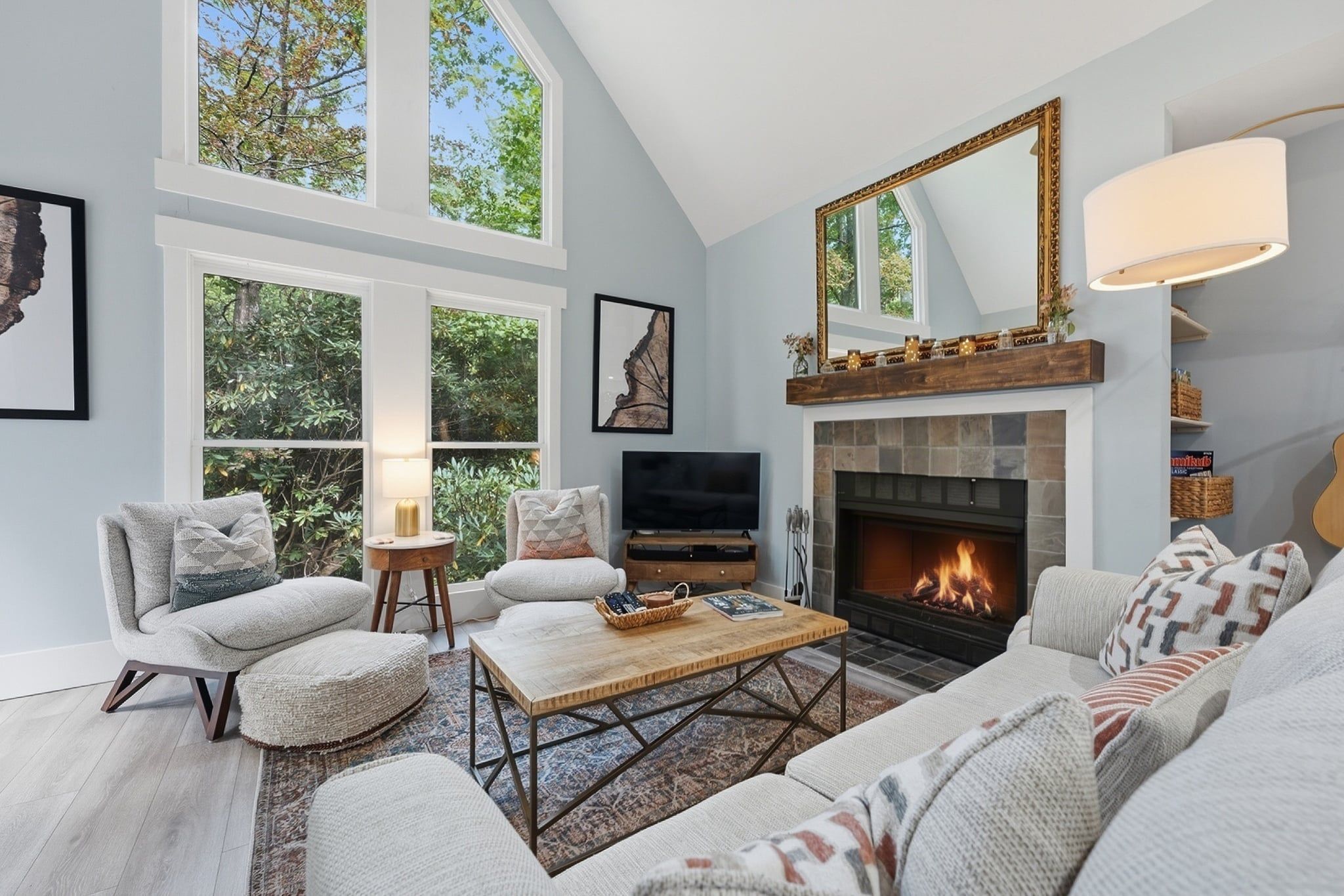 A modern living room with a fireplace, comfortable seating, and large windows.