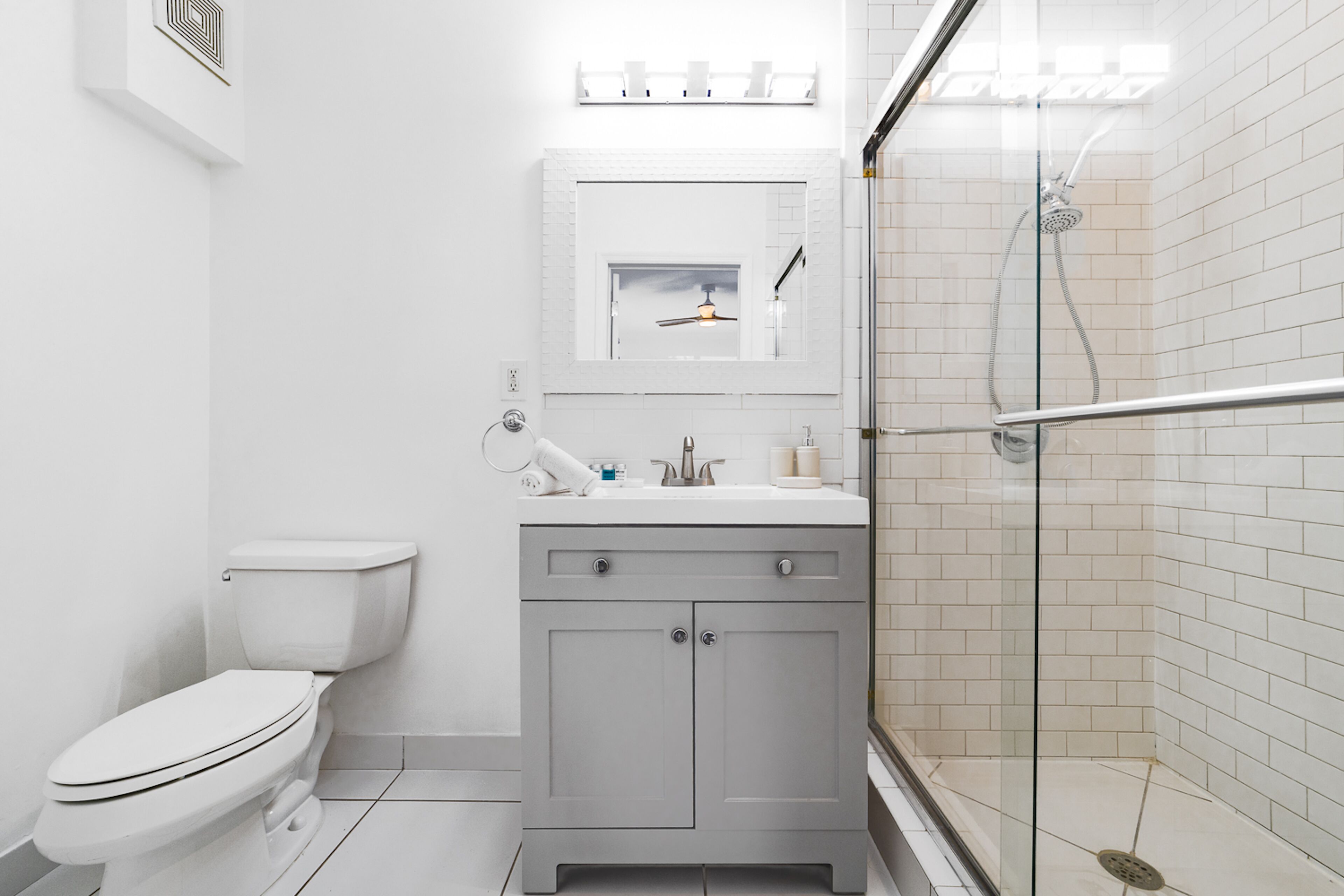 A modern bathroom with a toilet, a sink with a mirror, and a glass-enclosed shower area.