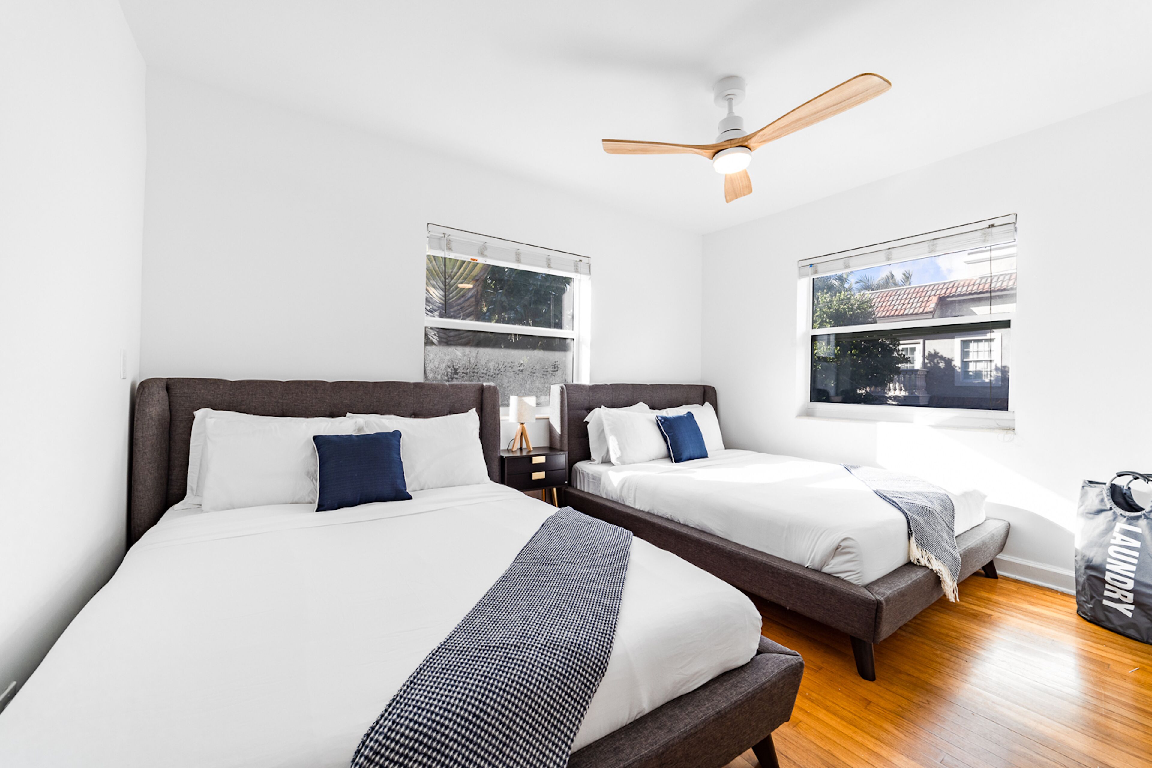 Una habitación de hotel con dos camas, un ventilador de techo y ventanas amplias.
