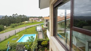 A residential property with a swimming pool, a view of a road, and a distant house. - Miralvalle Apartment (Valoria Cantabria)