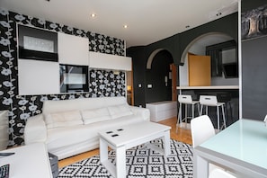 A modern living room with a white sofa, a coffee table, and a patterned rug.