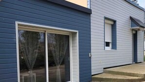 A house with a large sliding glass door and a small window. - Maison Individuelle en Bord de mer (Saint-Martin-en-Campagne)